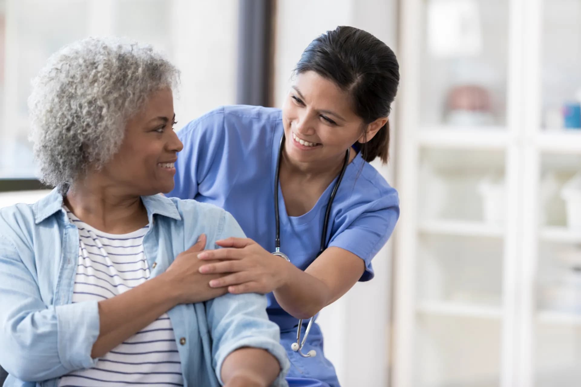 Pflegefachkraft betreut ältere Patientin — Empathie und Fachkompetenz