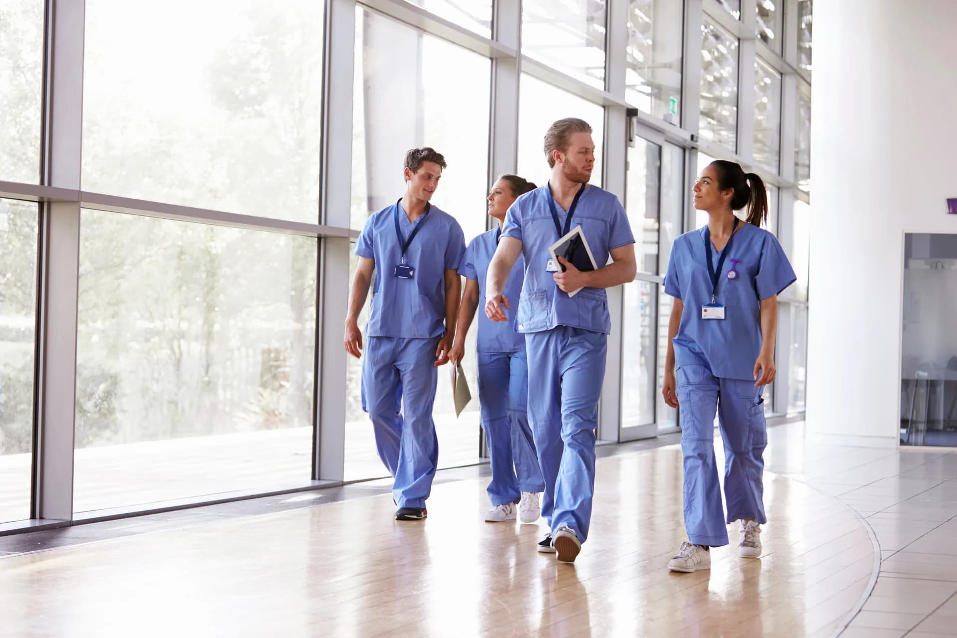 Internationale Pflegefachkräfte gehen gemeinsam durch eine moderne Klinik in Deutschland